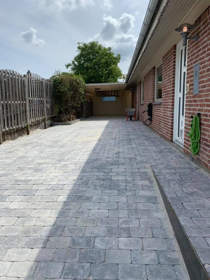 Færdig indkørsel i grå betonbrosten langs huset og ind mod carporten