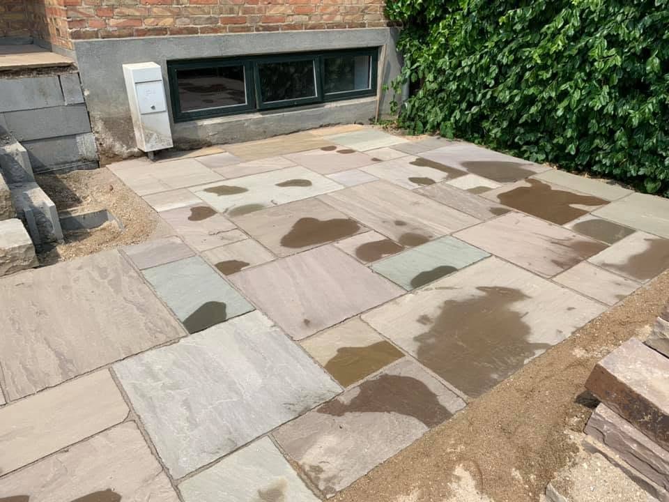 Færdig terrasse i indisk sandsten lagt i multiformat langs husets facade